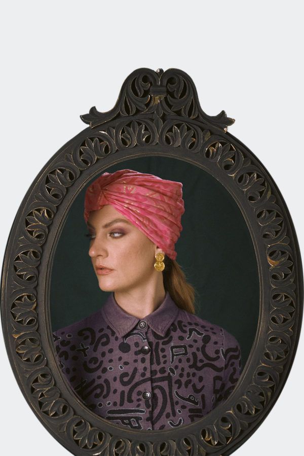Portrait of a model wearing a pink patterned luxury headpiece, turban