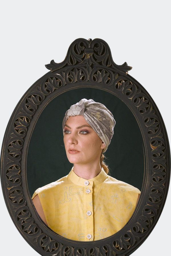 Portrait of a model wearing a grey patterned luxury headpiece, turban