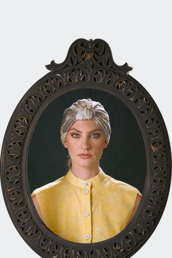 Portrait of a model wearing a grey patterned luxury headpiece, turban